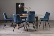 The Bentley Designs Turin Clear Tempered Glass 6 Seater Dining Table with Dark Oak Legs & 6 Fontana Blue Velvet Fabric Chairs with Grey Hand Brushing on Black Powder Legs Black Powder Coated Leg