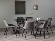 The Bentley Designs Mico Clear Tempered Glass 6 Seater Dining Table & 6 Seurat Grey Velvet Fabric Chairs with Sand Black Powder Coated Legs