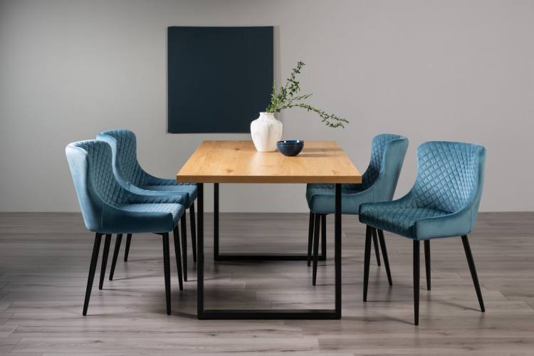 The Bentley Designs Ramsay Rustic Oak Effect Melamine 6 Seater Dining Table with U Leg & 4 Cezanne Petrol Blue Velvet Fabric Chairs with Sand Black Powder Coated Legs