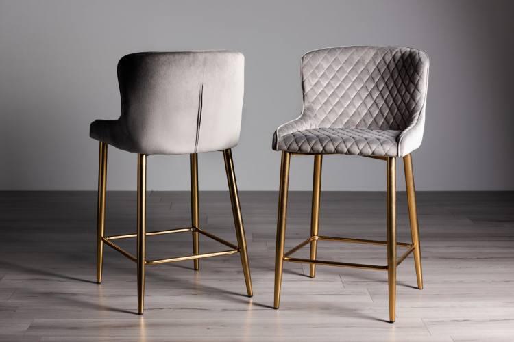 The Bentley Designs Cezanne Grey Velvet Fabric Bar Stools with Matt Gold Plated Legs on Display